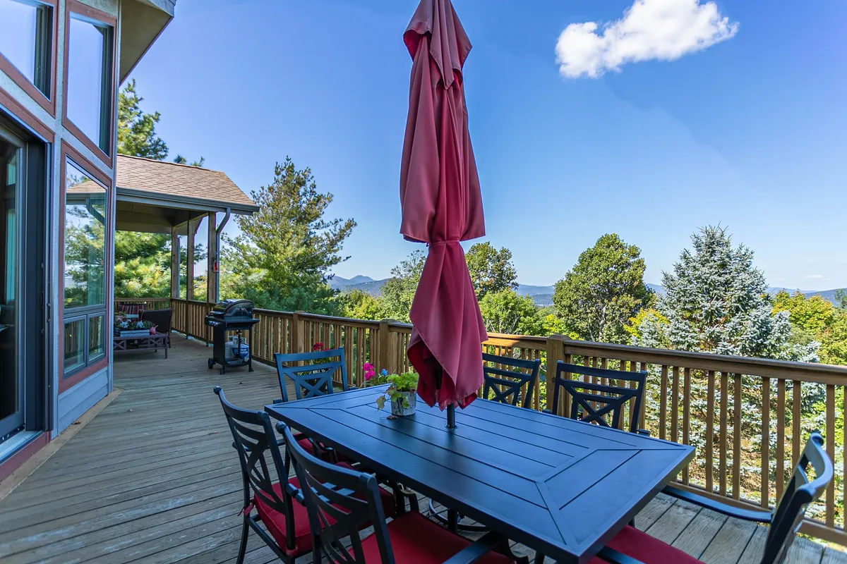 A spacious outdoor dining area with a table and umbrella, set against a stunning mountain backdrop and surrounded by greenery. The arrangement invites gatherings, meals, and celebrations, with the vast sky and mountains providing a dramatic setting for watching sunsets or fireworks.