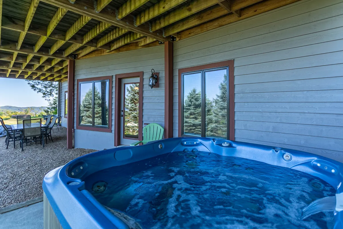 An exterior scene showing a bubbling hot tub on a patio with stunning mountain and landscape views. The inviting water and comfortable seating evoke après-ski relaxation and outdoor enjoyment.