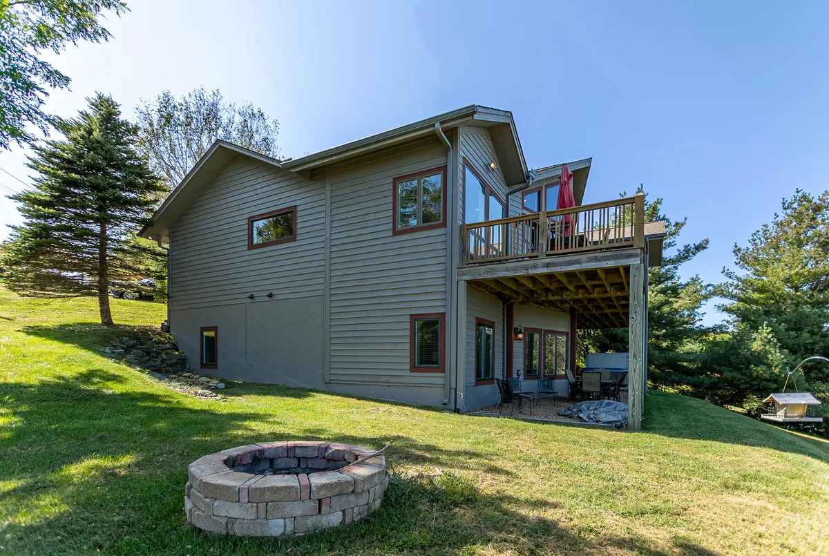 This exterior shot captures the home’s deck, fire pit, and a green lawn, offering an inviting spot for outdoor gatherings. The vista extends toward the distance, hinting at the mountain environment and the expansive outdoor space available for relaxation or play.