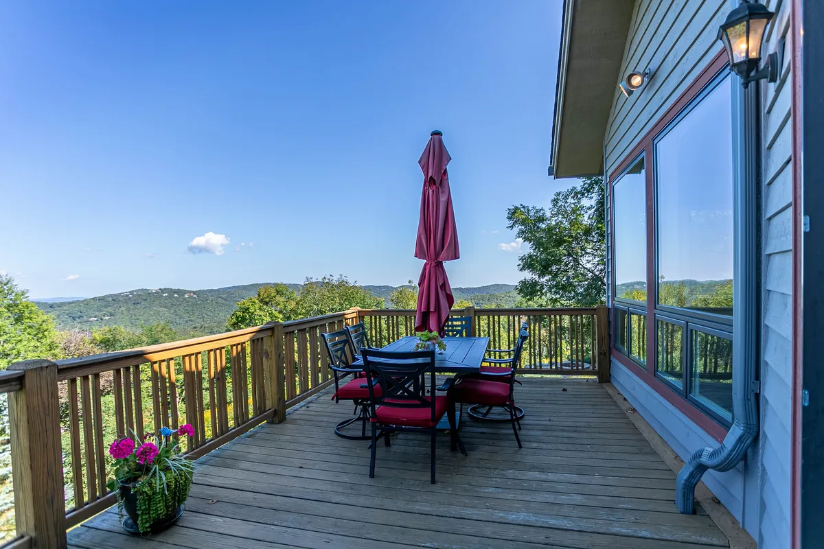 A welcoming outdoor dining area with a table and chairs shaded by a red umbrella, set against a backdrop of striking mountain views. The setting is ideal for family gatherings, stargazing at night, or enjoying meals with panoramic scenery.