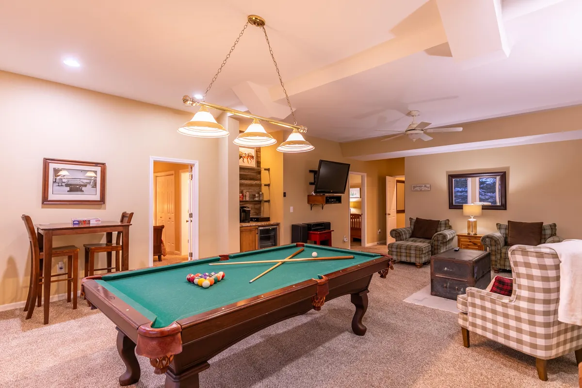 A vibrant entertainment space featuring a pool table, a well-appointed bar area, and a comfortable seating arrangement. The lighting and layout invite guests to enjoy games, socialize, and unwind, making it an ideal spot for group fun and relaxation.