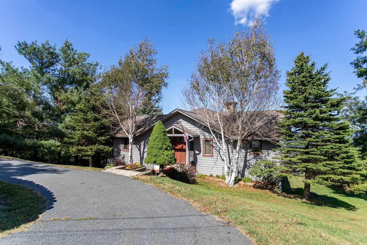 This exterior shot features the home's front door, neatly trimmed bushes, and a driveway leading up to the house. The inviting porch offers a glimpse of the serene neighborhood, suggesting easy access for leashed dog walks and a welcoming space to start or end an outdoor adventure.