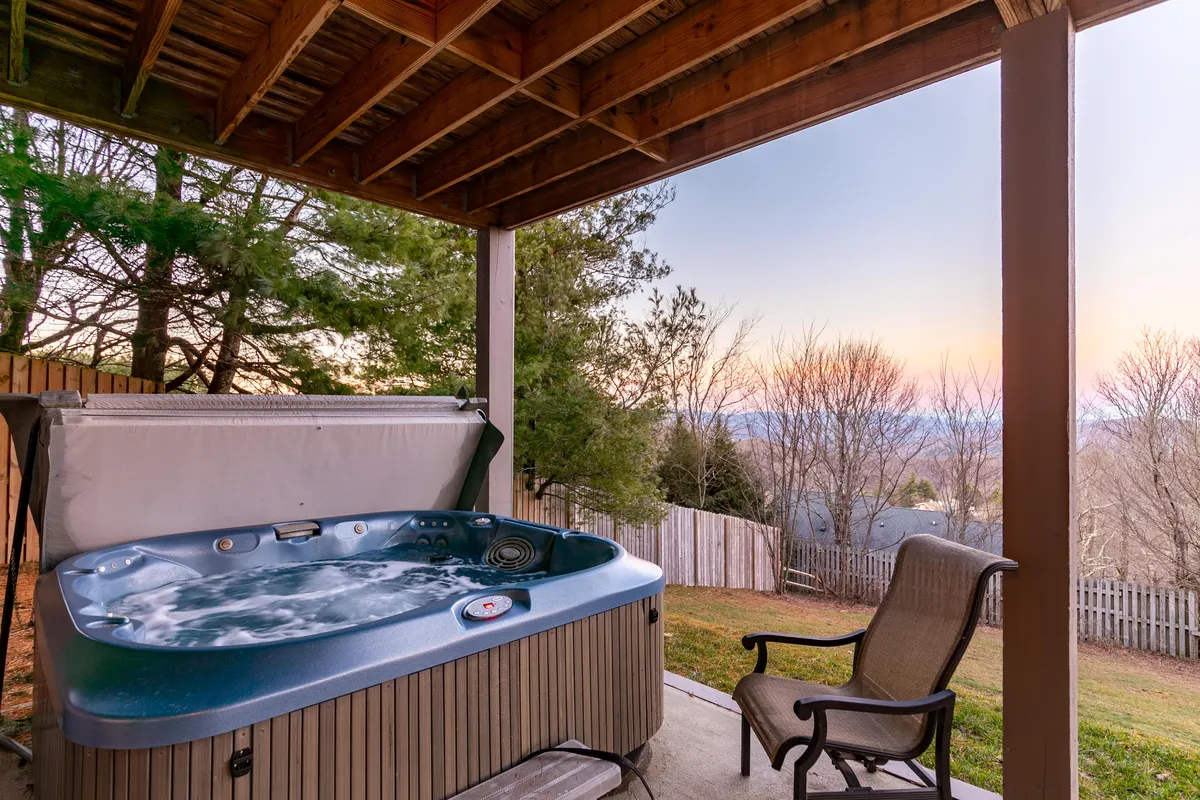This tranquil exterior image highlights a private hot tub surrounded by trees, with an outdoor chair nearby. The setting conveys a peaceful retreat, ideal for relaxing after a day on local trails or spending time with your pet in nature.