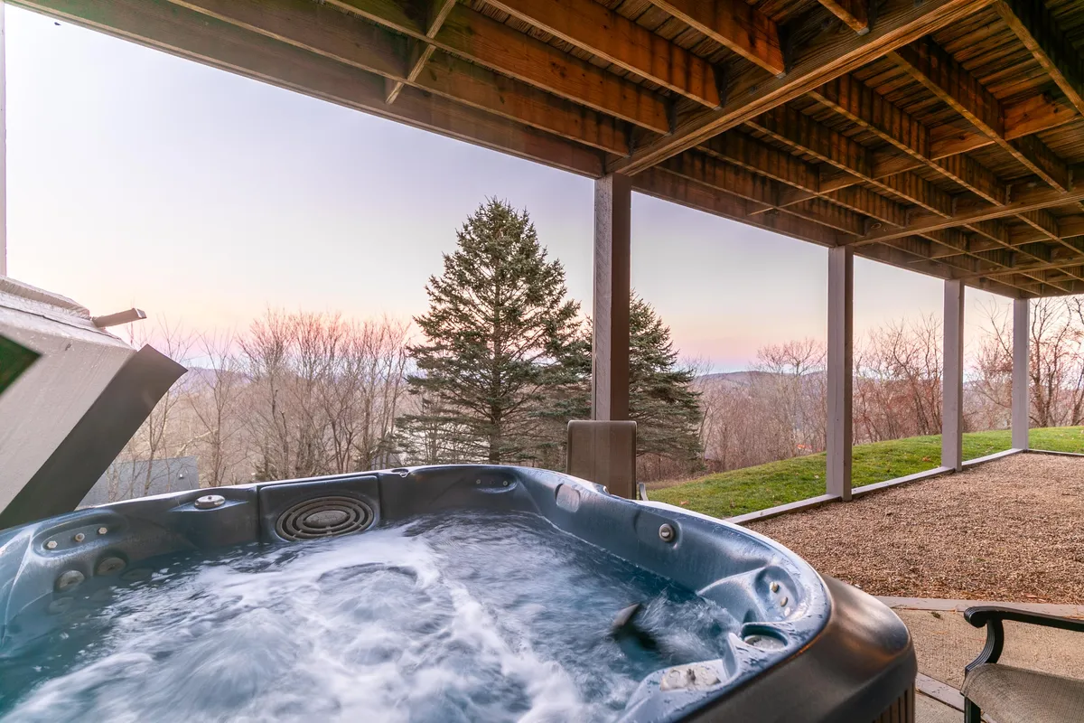 This exterior shot focuses on the hot tub with a backdrop of a vibrant sunset and stunning natural landscape. The scene evokes a sense of tranquility and group enjoyment, ideal for socializing or unwinding after a day exploring the mountains.